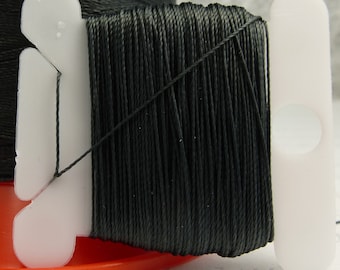 Puede incluir: Una bobina de hilo negro enrollada en una bobina de plástico blanco. El hilo está enrollado alrededor de la bobina y está listo para ser utilizado para coser o hacer manualidades.