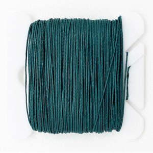 May include: A spool of dark green waxed cotton cord, wound on a white plastic spool.
