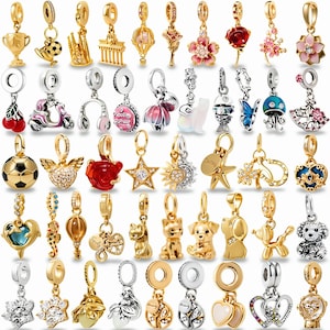 May include: A selection of gold and silver charm pendants with diverse designs, including flowers, animals, and geometric shapes. Some charms feature colourful accents, such as red, pink, and blue. The charms are designed to be added to a bracelet or necklace.