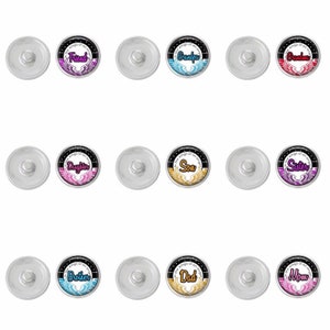 May include: Twelve silver snap buttons with black backgrounds and colorful angel wings. Each button features the text "The wings of an angel" and a different word, such as "Friend", "Grandpa", "Daughter", "Son", "Sister", "Brother", "Dad", and "Mom".