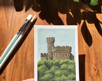 May include: A hand-painted watercolor illustration of a brown stone castle with a tower, surrounded by green trees. The painting is signed "13/30 Castle".