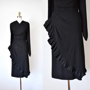 May include: A black dress with a ruffled hem and long sleeves. The ruffles are asymmetrical and create a dramatic look.