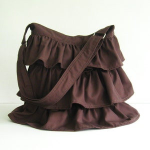 May include: A brown ruffled shoulder bag with a long brown strap.