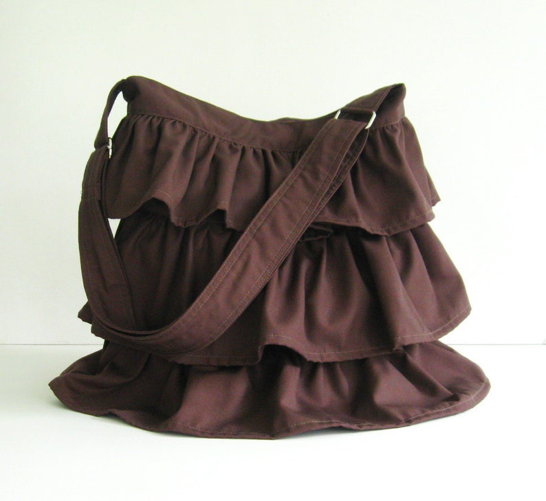 May include: A brown ruffled shoulder bag with a long brown strap.