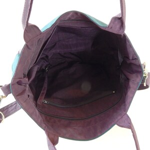 May include: A purple tote bag with a zippered pocket on the inside. The bag has a long strap and two shorter handles.