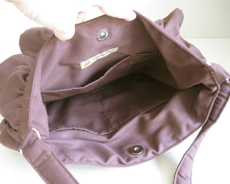 May include: The inside of a brown canvas bag with a zipper closure and a small pocket. The bag has a label that reads 'Simply Green'.
