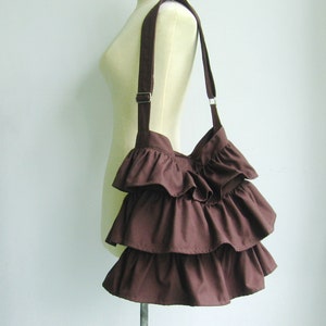 May include: A brown ruffled tote bag with a long strap.