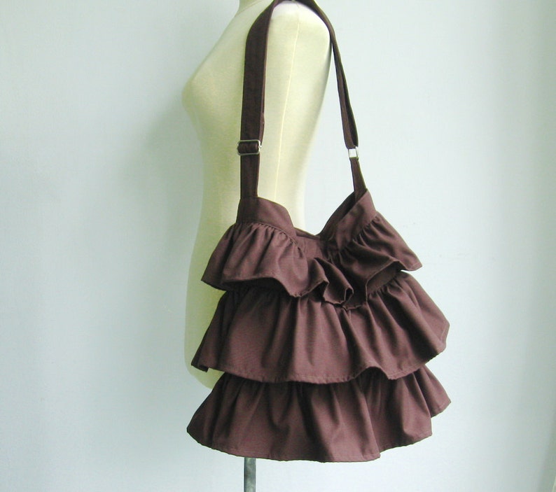 May include: A brown ruffled tote bag with a long strap.