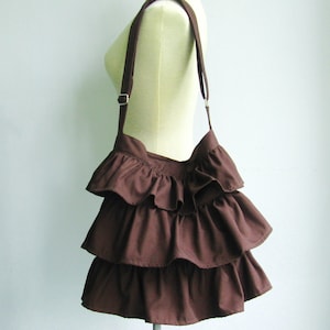 May include: A brown ruffled shoulder bag with a long strap.