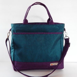 May include: A teal and purple tote bag with a shoulder strap and a small pocket on the front. The bag has a label that says "TippyT".