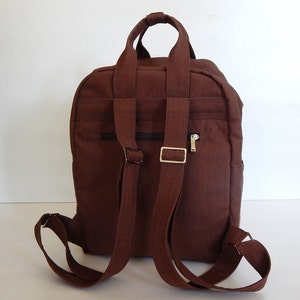 May include: A brown canvas backpack with adjustable straps and a zippered pocket on the front.