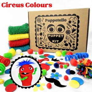May include: A Puppetello puppet kit in a brown cardboard box with black graphics, including a red puppet with blue hair, green arms, and various craft supplies like felt shapes, pom-poms, googly eyes, and colorful fabric squares.