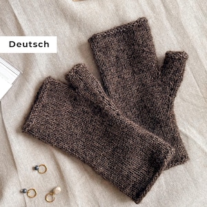 Könnte beinhalten: Ein Paar braune Fingerhandschuhe aus Strickmaterial. Die Handschuhe werden auf einer beigen Leinenoberfläche mit Stricknadeln im Hintergrund gezeigt. Das Wort "Deutsch" ist im Bild zu sehen.