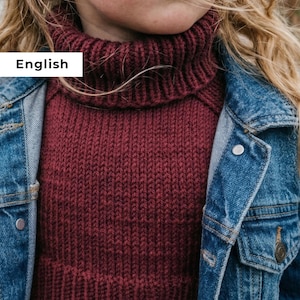 Puede incluir: Primer plano de un niño con un jersey de cuello alto burdeos y una chaqueta vaquera. El jersey está tejido con una textura acanalada. La chaqueta vaquera tiene un diseño clásico con costuras visibles y un bolsillo abotonado.