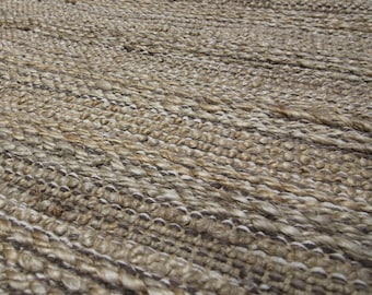 May include: Close-up of a woven rug with a textured surface. The rug is made of natural fibres, with a mix of light and dark brown tones. The weave pattern creates a striped effect, suitable for home decor.