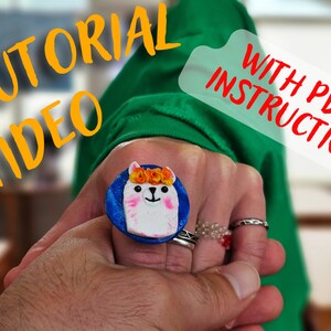 May include: A white ring with a blue base and a white llama with orange flowers on its head. The text "WITH PDF INSTRUCTION" is visible in the background.