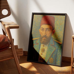 May include: Framed portrait of a man in a red fez and blue jacket with gold embellishments. The artwork is displayed in a black frame, leaning against a wall next to a wooden chair and side table.