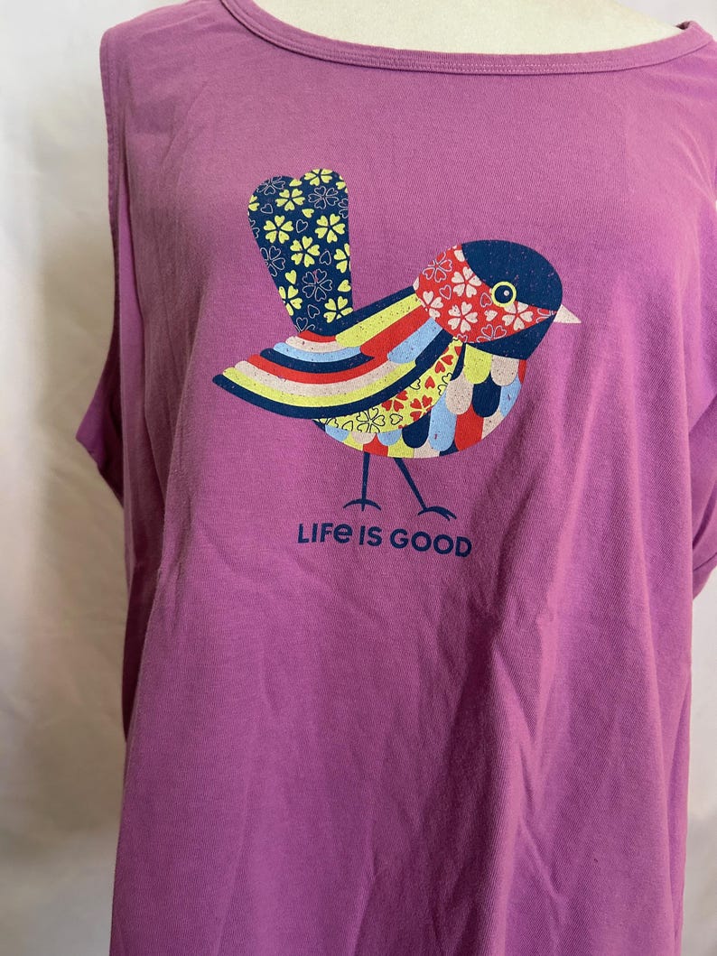 May include: Purple t-shirt with a colorful bird graphic and the text "Life is Good".
