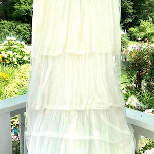 May include: A white tiered maxi skirt with a wide waistband and a delicate, sheer fabric. The skirt is made of multiple layers of tulle, creating a flowing and romantic look.