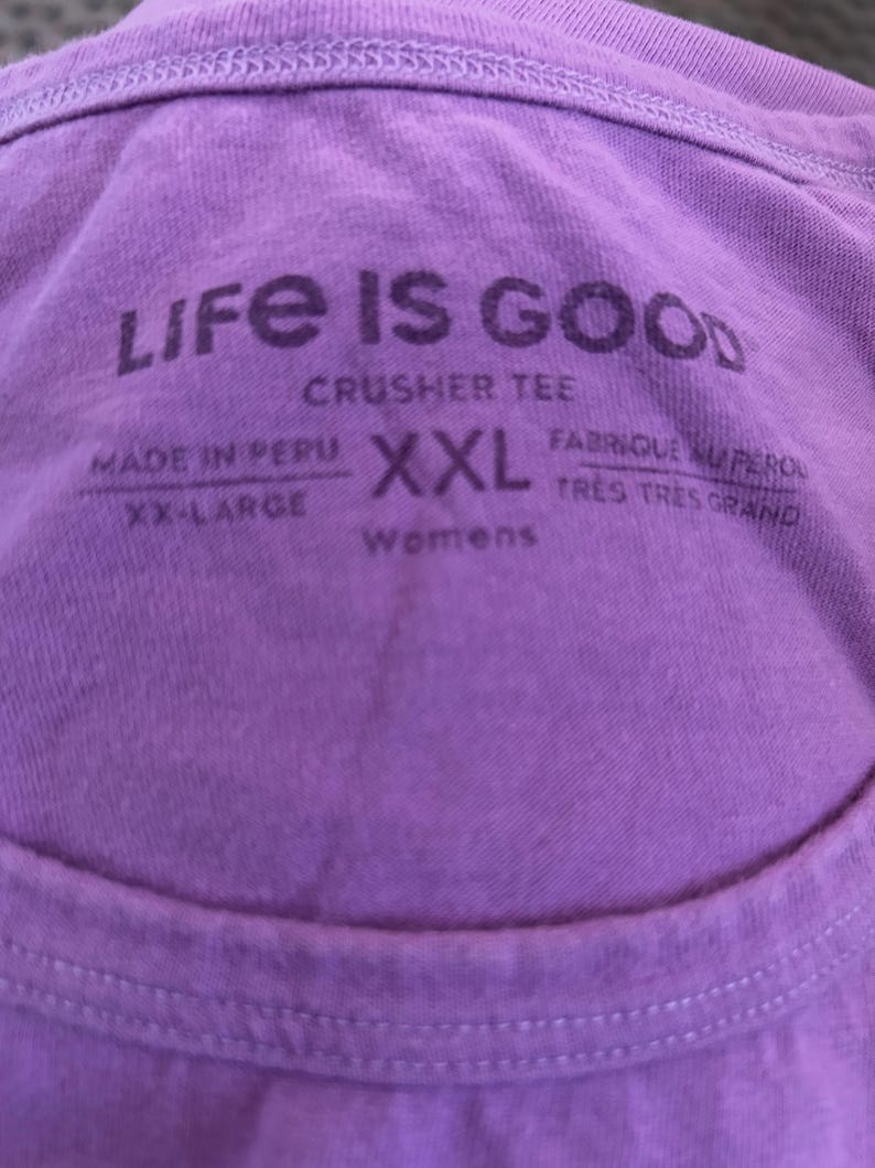 May include: Purple Life is Good crusher tee shirt tag with the text "Made in Peru, XX-Large, XXL, Womens, Fabrique au P&eacute;rou, Tr&egrave;s Tr&egrave;s Grand".