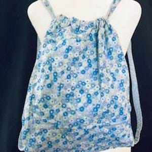 May include: A blue drawstring backpack with a white and blue floral pattern. The backpack has adjustable straps.