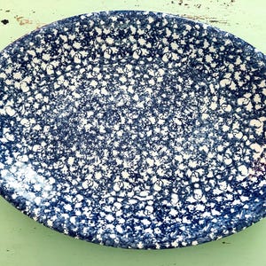 May include: Oval serving platter with a blue and white speckled pattern. The ceramic dish has a dark blue background with white speckles, creating a textured appearance. The platter is suitable for serving food.