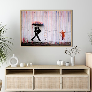 Lienzo de arte callejero con lluvia de colores, grafiti estilo Banksy, impresión urbana moderna, hombre con paraguas y niño, decoración de pared vibrante.