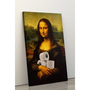 Könnte beinhalten: Ein Leinwanddruck der Mona Lisa, die drei Rollen weißes Toilettenpapier hält. Das Kunstwerk ist eine Parodie des berühmten Gemäldes, wobei der Ausdruck und die Kleidung des Subjekts gleich bleiben.