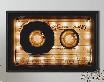 May include: A rectangular wall art piece featuring a backlit, oversized TDK 90 cassette tape design. The clear plastic casing reveals internal spools and gears, illuminated by warm golden light, with the text TDK 90, IEC I/TYPE I, and LOW NOISE HIGH OUTPUT.