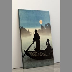 May include: A canvas print of a Japanese woodblock print depicting a boat on a river at night. The artwork features two figures in the boat, a full moon, and a bridge in the background. The color palette includes shades of blue, black, and beige.