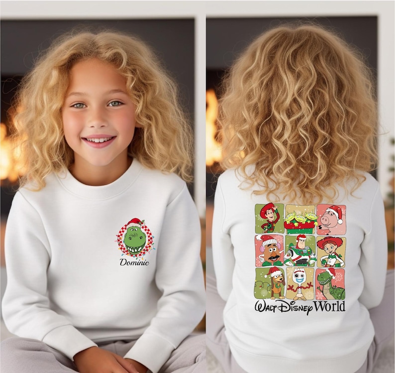 Puede incluir: Sudadera blanca con un dise&ntilde;o del Grinch con gorro de Pap&aacute; Noel y el nombre "Dominic" en la parte delantera. La parte trasera muestra una cuadr&iacute;cula de personajes de Toy Story con gorros de Pap&aacute; Noel y el texto "Walt Disney World".