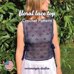 Op de afbeelding: Een marineblauwe top van bloemenkant met een haakpatroon. De mouwloze top heeft een vierkant patroon met bloemaccenten en marineblauwe linten aan de zijkanten. De tekst "floral lace top" en "Crochet Pattern" worden bovenaan weergegeven.