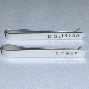 May include: Two silver tie bars, one engraved with "π 3.14159" and the other with "E=MC2".