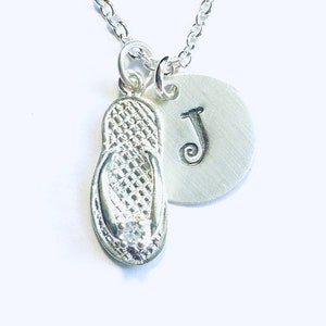 May include: Silver necklace with a flip-flop charm and a round charm with the letter J.