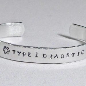 May include: Silver bracelet with a star of life symbol and the text "TYPE 1 DIABETIC" engraved on it.