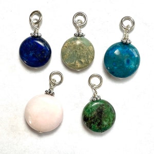 May include: Five round gemstone pendants with silver bail and bead accents. The stones are blue, green, light green, pink, and dark green.