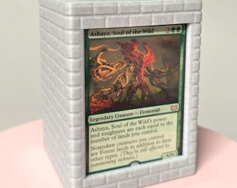 May include: A white, brick-patterned card holder with a green clover on top. The holder displays a Magic: The Gathering card titled "Ashaya, Soul of the Wild." The card features a colorful illustration of a creature.