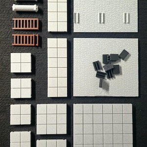 May include: An assortment of miniature building components, including white square tiles, rectangular wall sections, and brown ladders. Also included are white cylindrical pieces and black connector pieces. The pieces are arranged on a dark surface.