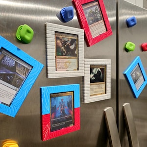 May include: A collection of colorful magnetic picture frames and magnets are attached to a stainless steel surface. The frames hold trading cards and are in various colors, including red, blue, and white. The magnets are in the shape of small backpacks and cubes.