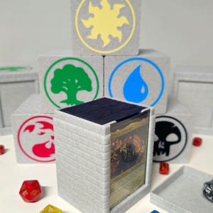 May include: A gray card holder with a brick pattern, holding a Magic: The Gathering card. Gray blocks with colored symbols are stacked behind the holder. Dice in various colors are scattered around the holder.