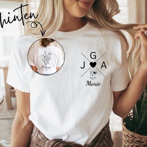 May include: White t-shirt with black graphic designs. The front features initials, a heart, two wine glasses, and the name "Marie." The back has a floral design and the word "Braut." A small circle shows the back design. The word "hinten" is at the top.