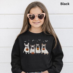 Op de afbeelding: Zwart sweatshirt met een afbeelding van vier Franse Bulldogs in spookkostuums, elk met een pompoen. Het woord "Black" staat rechtsboven gedrukt. De persoon draagt een hartvormige zonnebril.