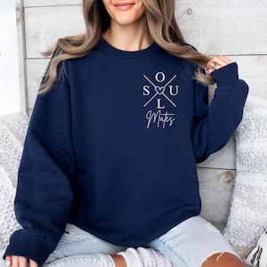 May include: A navy blue crew neck sweatshirt. The front features the white text "SOUL Mates" in a cross design with a heart symbol. The sweatshirt is a dark blue colour.