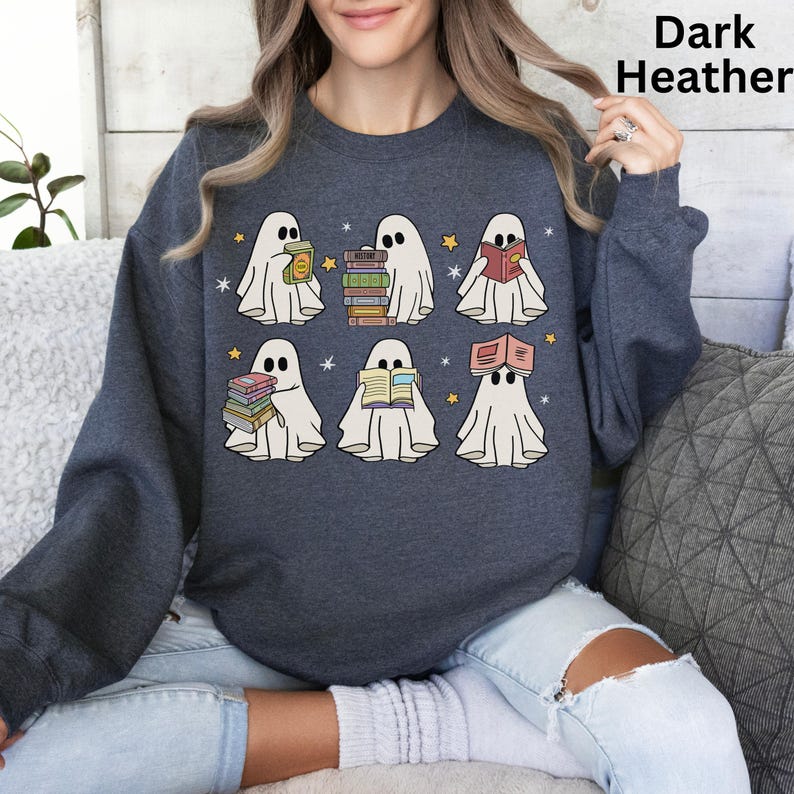 May include: Dark heather gray sweatshirt featuring a graphic of six cartoon ghosts reading books. Each ghost is white with black eyes and is holding or wearing a stack of books. The text "Dark Heather" is in the upper right corner.