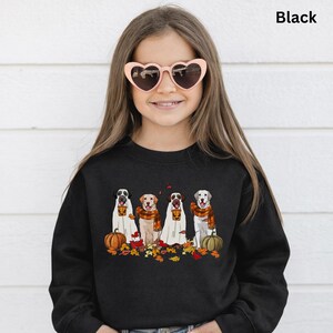 Op de afbeelding: Zwart sweatshirt met een afbeelding van vier honden verkleed als geesten, met oranje sjaals en omringd door pompoenen en herfstbladeren. Het woord "Black" staat rechtsboven gedrukt.