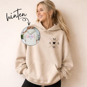 May include: A beige hoodie with a front pocket and a hood. The front features a black design with the letters "MAMA" and a heart. The back of the hoodie, shown in a smaller image, has the word "MAMA" in colorful letters and a heart.
