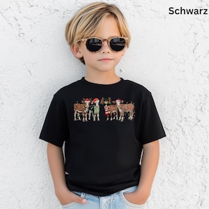 Puede incluir: Camiseta negra con un dise&ntilde;o festivo de vacas con gorros de Pap&aacute; Noel y decoraciones navide&ntilde;as. La palabra "Schwarz" est&aacute; impresa en la esquina superior derecha. La camiseta la lleva un ni&ntilde;o con gafas de sol.