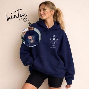 May include: A navy blue hoodie with a front pocket and a hood. The front features the letters "M A M A" in a cross design with a heart in the center, and the text "Leo est. 2026". The back of the hoodie has a floral design with the text "Wildflowers".
