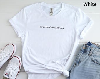 May include: White t-shirt with the text "Ihr werdet Oma und Opa :) ". The shirt is paired with blue jeans and white sneakers. The t-shirt is made of a soft material and is perfect for casual wear.