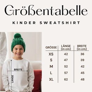 May include: A child wearing a white sweatshirt and a green knit cap. The image includes a size chart in German, with measurements in centimeters for length and width. The chart lists sizes XS to XL, with corresponding measurements.